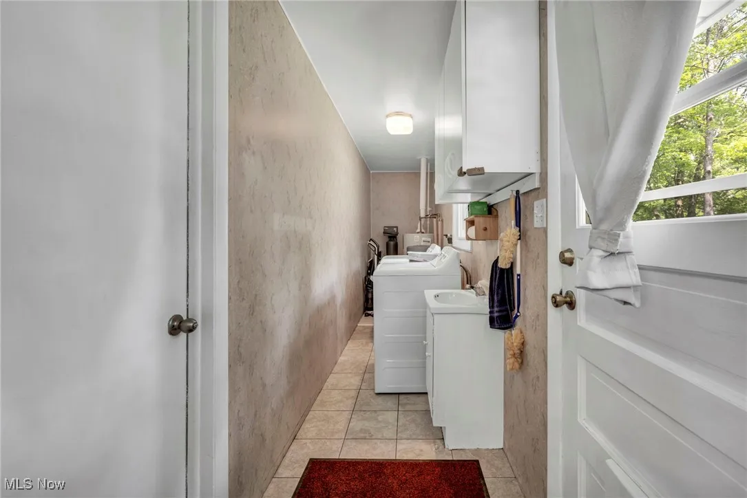 Laundry area featuring washing machine and dryer, light tile patterned flooring, and cabinet space