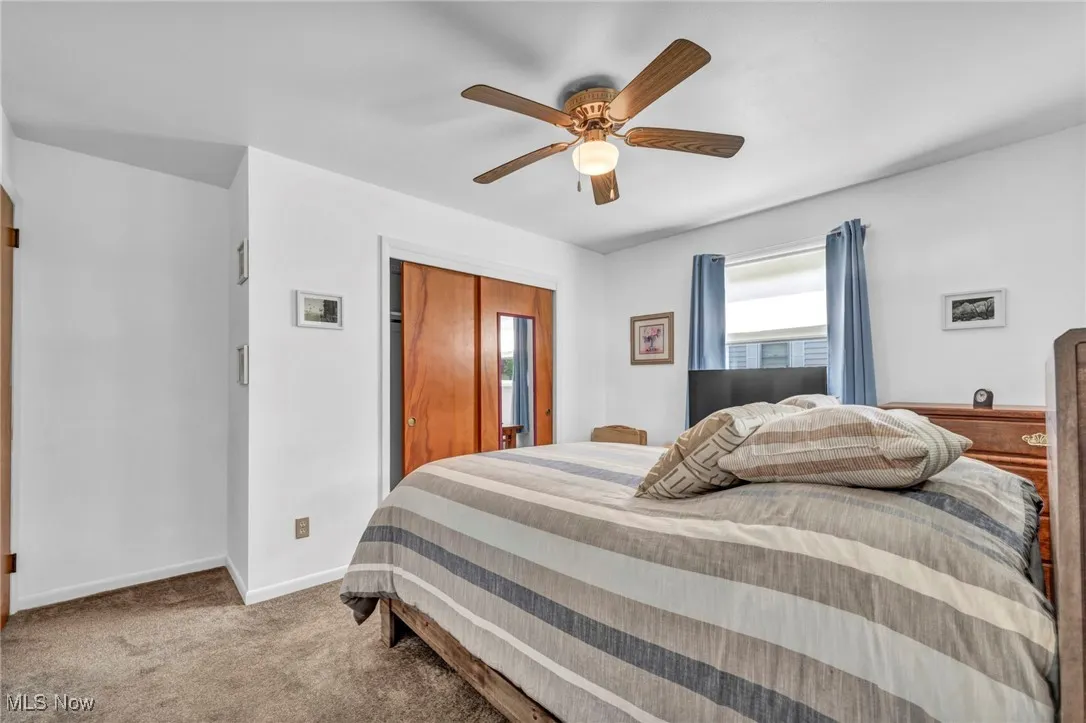 Carpeted bedroom with a ceiling fan and a closet