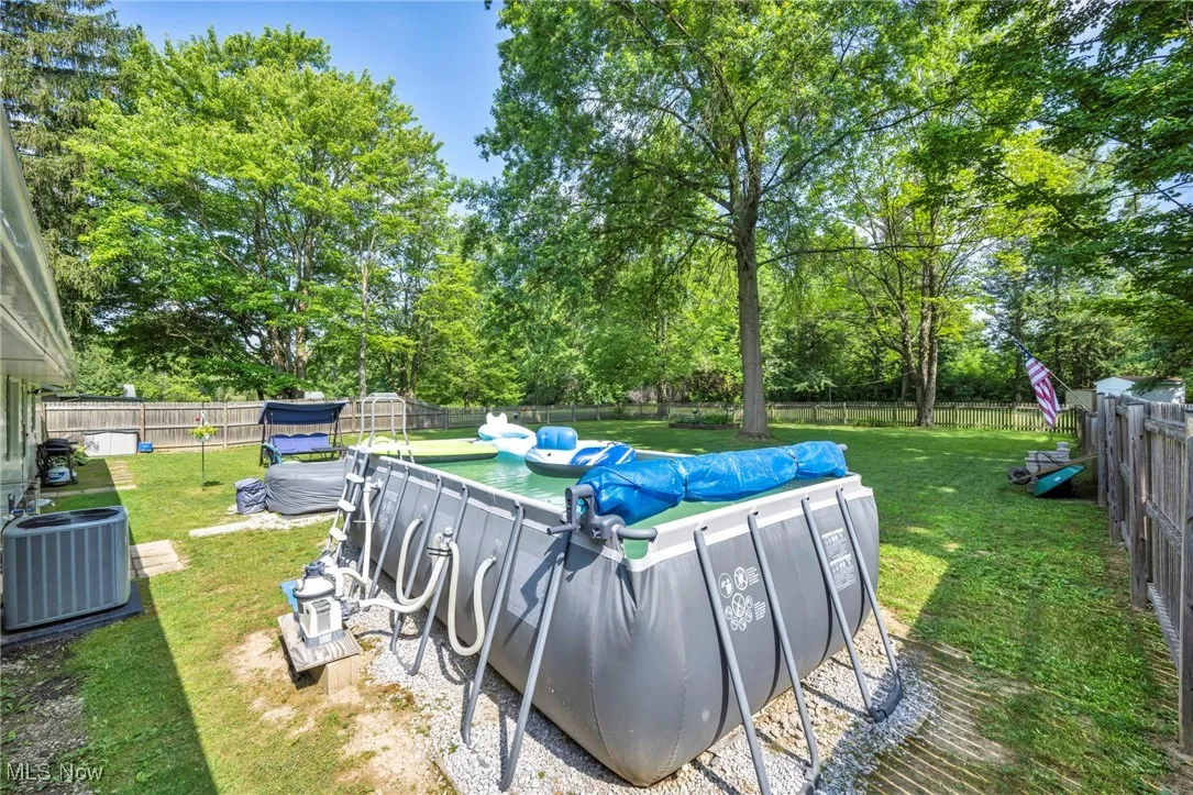 View of swimming pool featuring a fenced backyard and view of wooded area