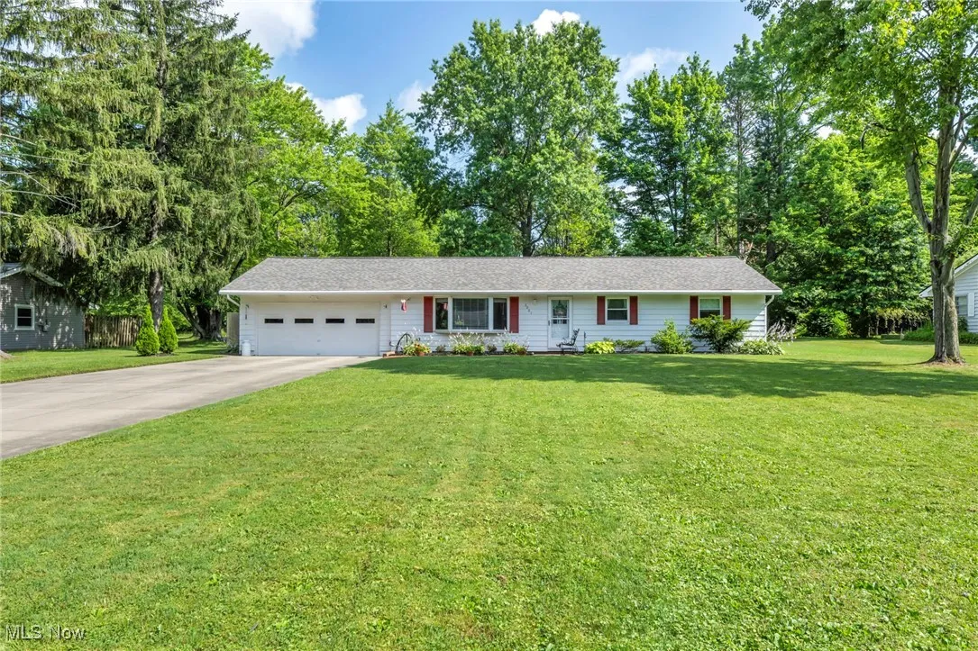 Ranch-style house featuring a garage, driveway, and a front lawn