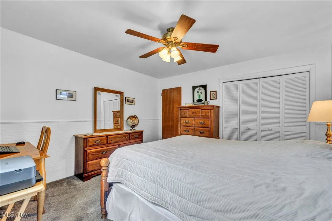 Bedroom with carpet floors, wainscoting, and ceiling fan