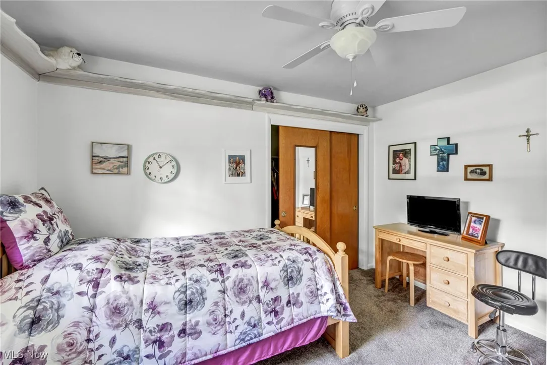 Carpeted bedroom with ceiling fan and an office area