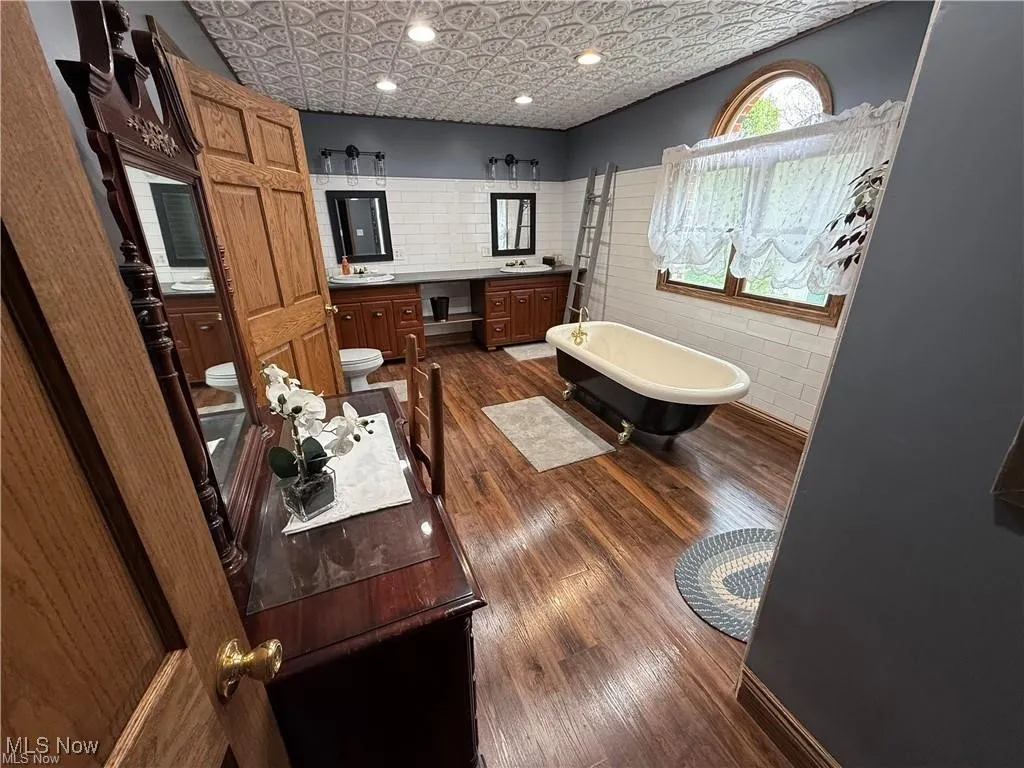 Full bath featuring an ornate ceiling, a freestanding tub, vanity, and wood finished floors