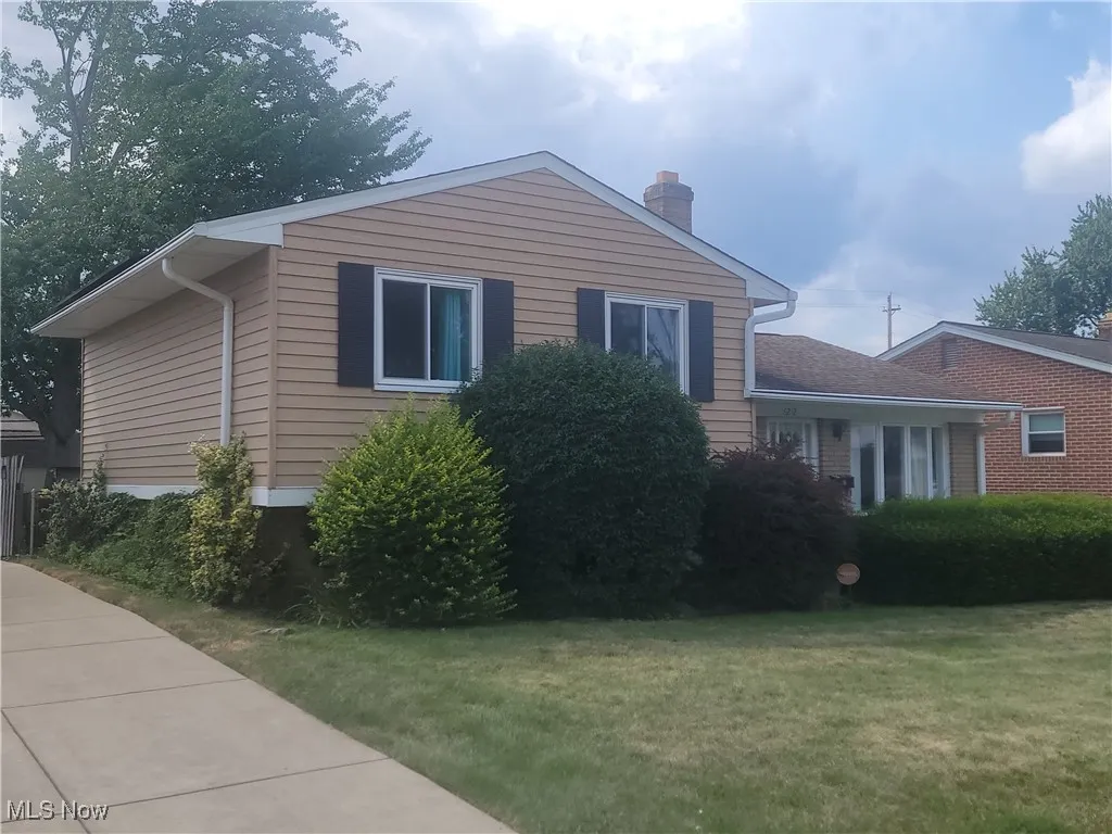 View of side of home featuring a chimney and a lawn