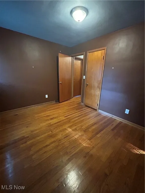 Unfurnished bedroom featuring wood finished floors and baseboards