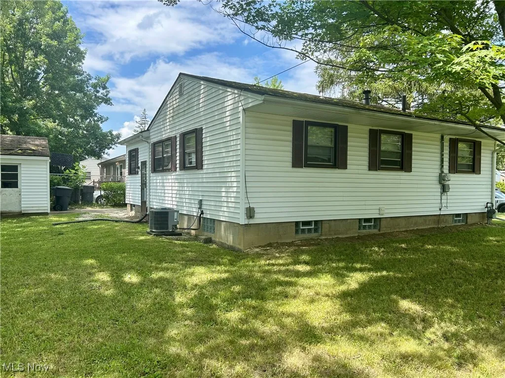 View of side of property with a yard and an outdoor structure
