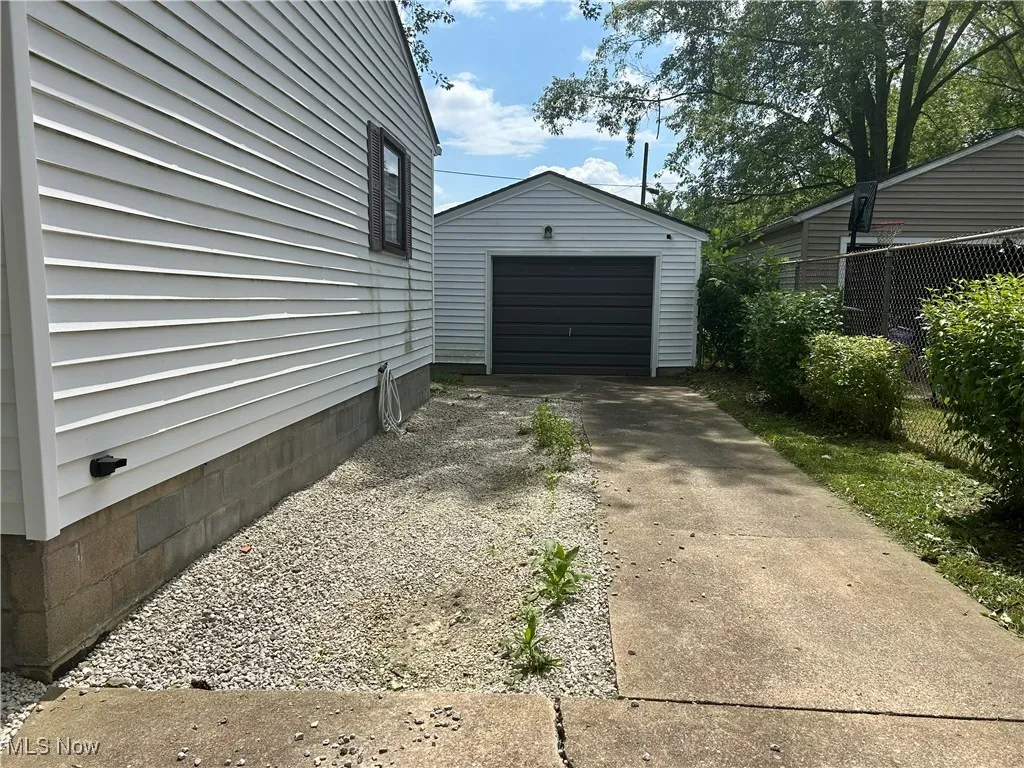 View of property exterior featuring driveway, a garage, and an outbuilding