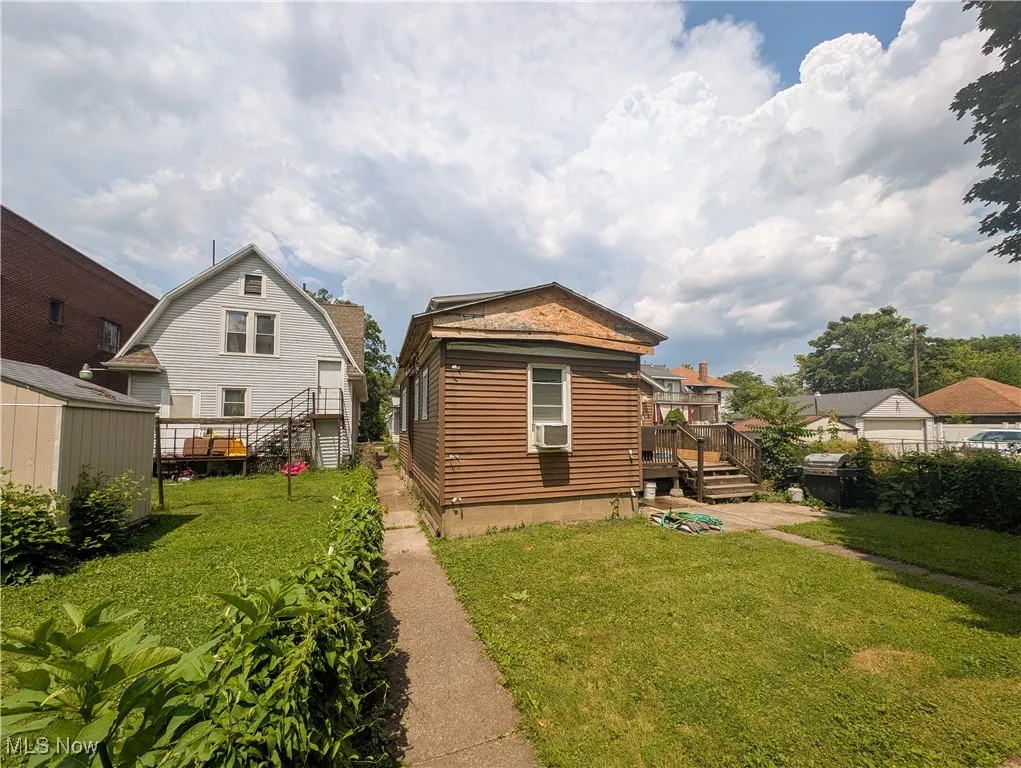 Rear view of property featuring a yard, a wooden deck, cooling unit, and a shed