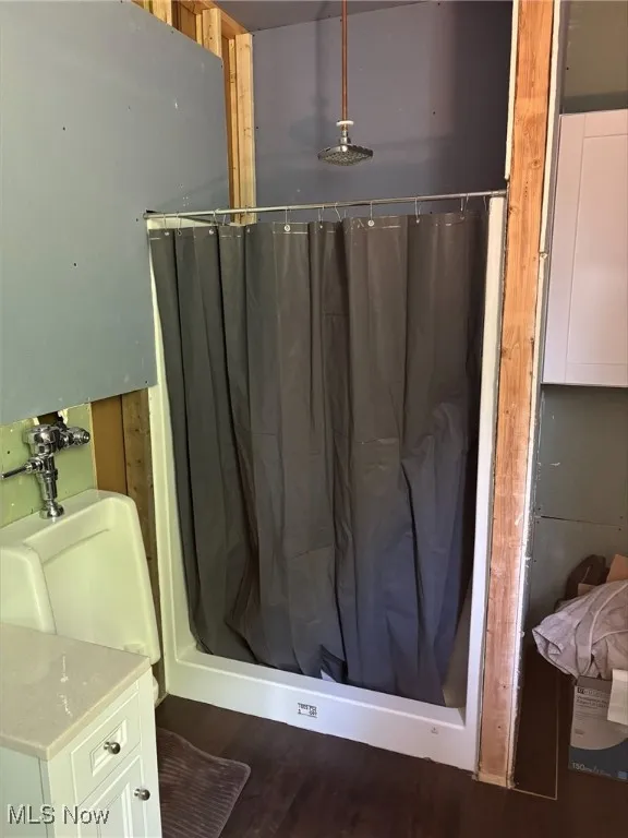 Bathroom with a shower with curtain and wood finished floors