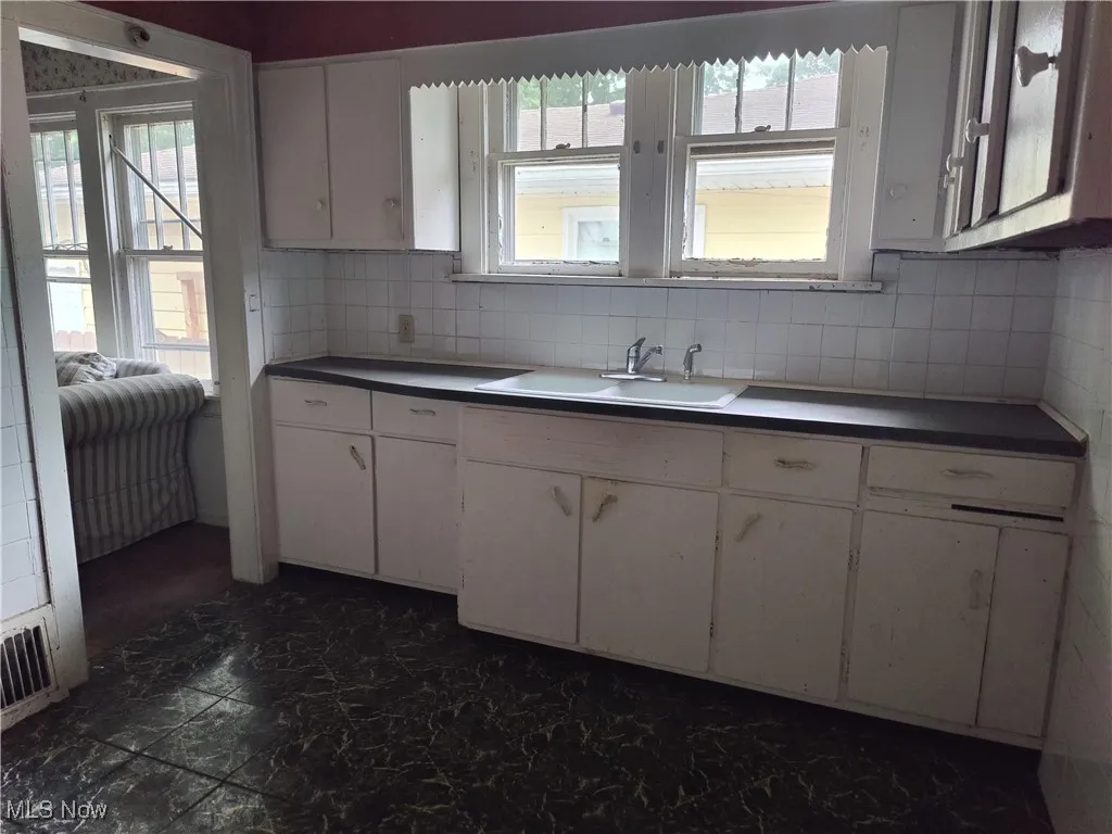 Kitchen featuring backsplash and white cabinets