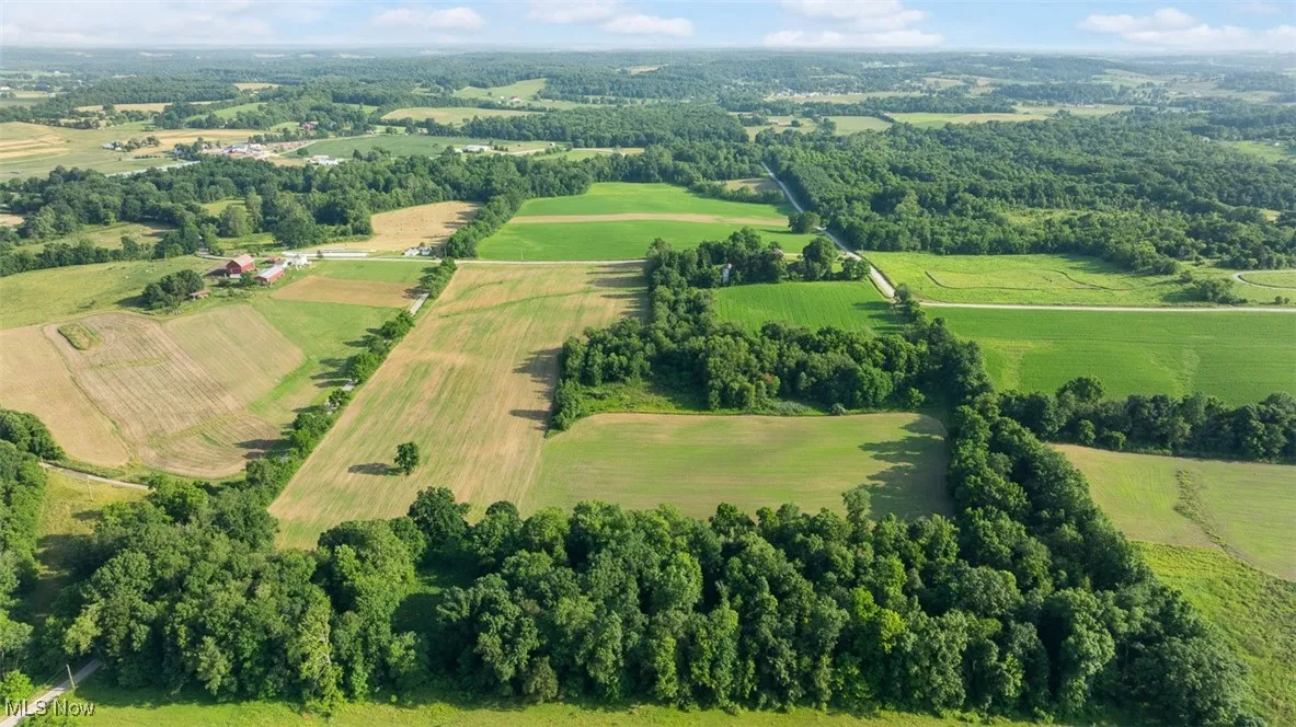 Aerial view of property and surrounding area featuring rural landscape and large plots for crops