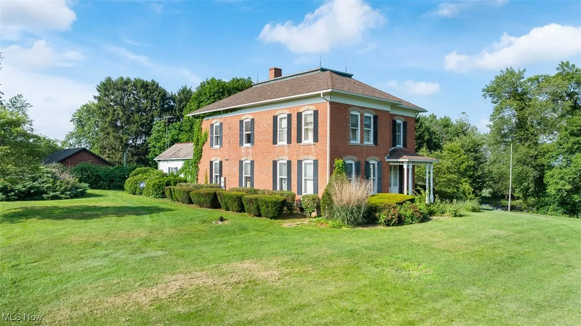 View of property exterior featuring a chimney, a yard, and brick siding