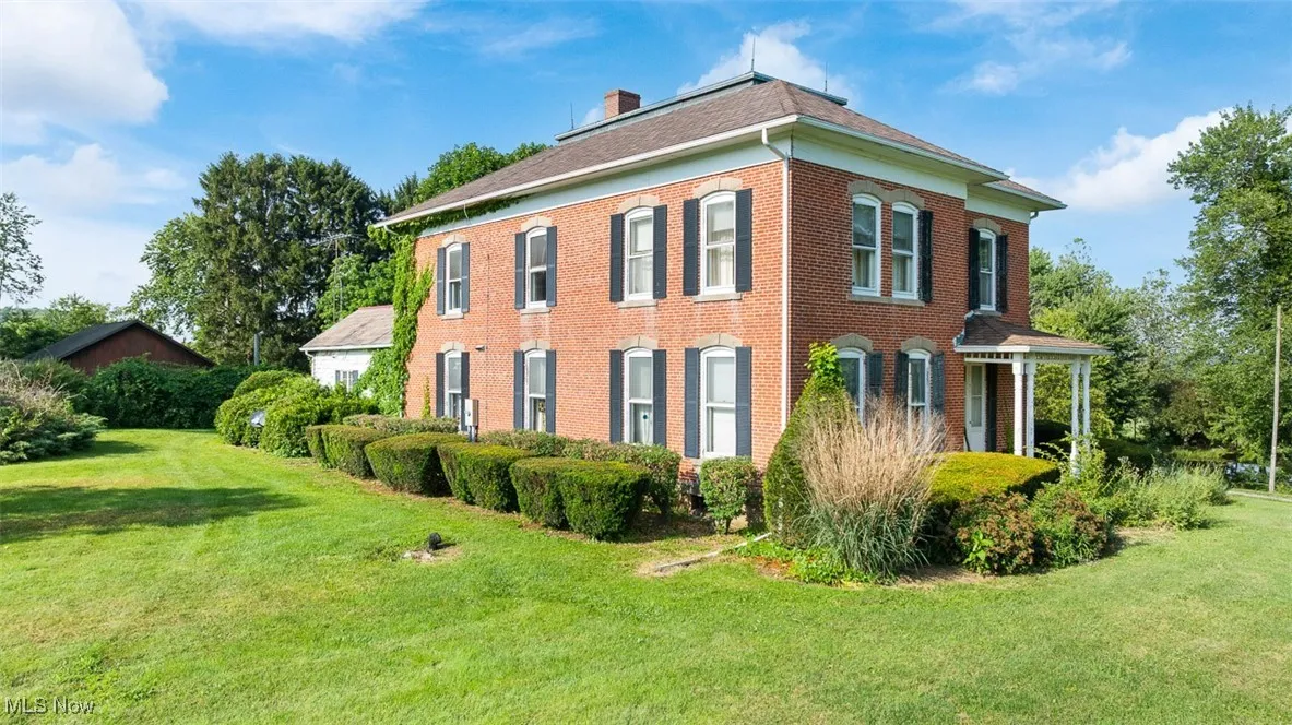 View of front of home featuring a chimney, brick siding, and a yard