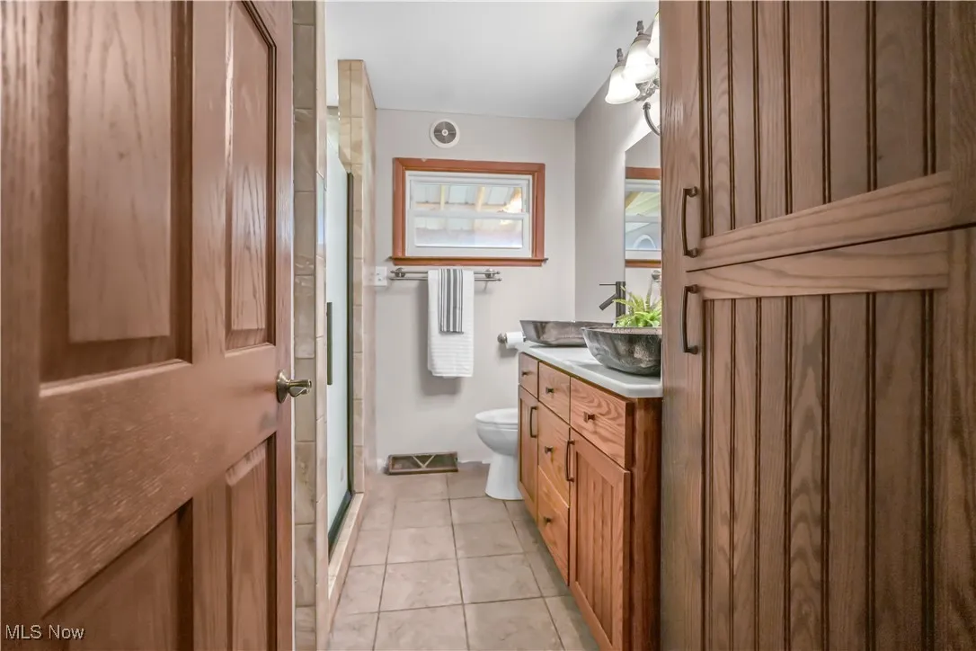 Bathroom with vanity, tile patterned flooring, and a shower stall