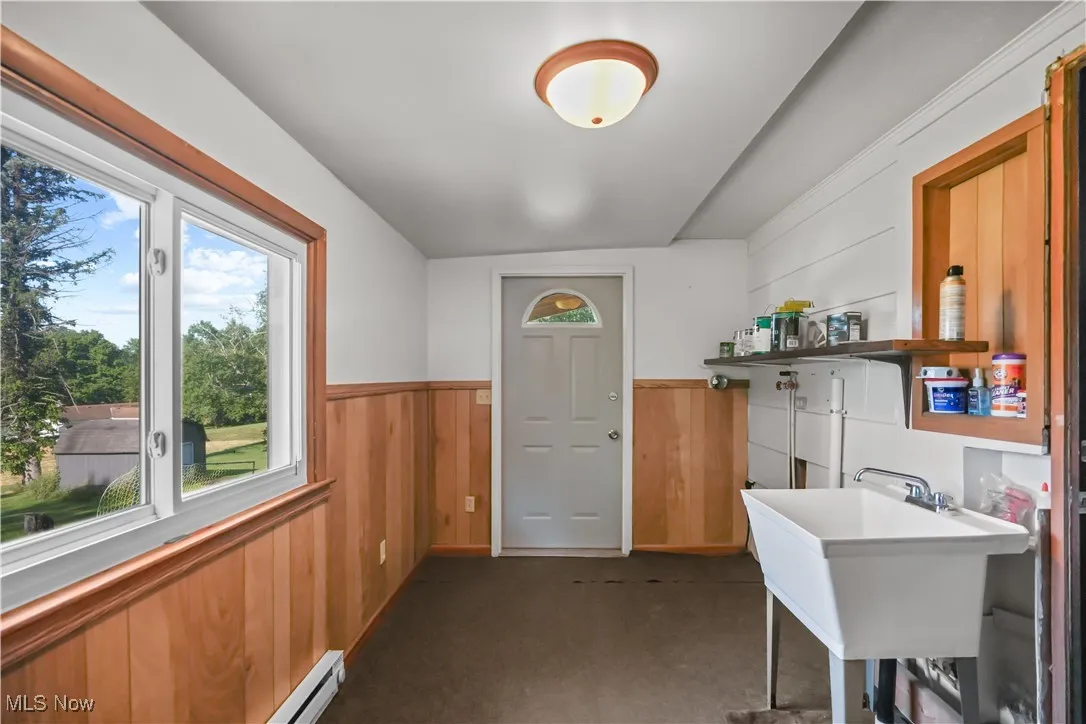 Office space featuring wainscoting, dark colored carpet, wood walls, and a baseboard heating unit