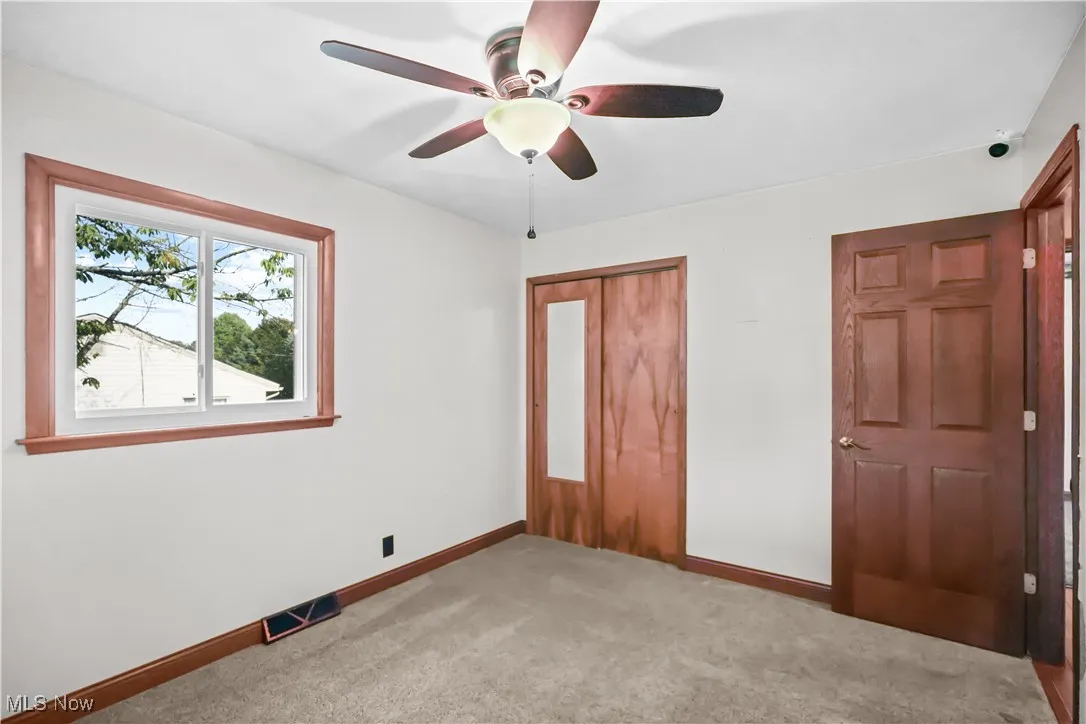 Unfurnished bedroom featuring a closet, light carpet, and a ceiling fan