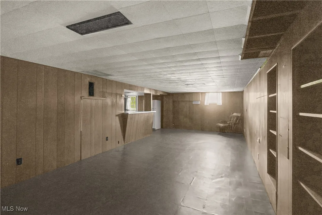 Below grade area with wooden walls and tile patterned floors