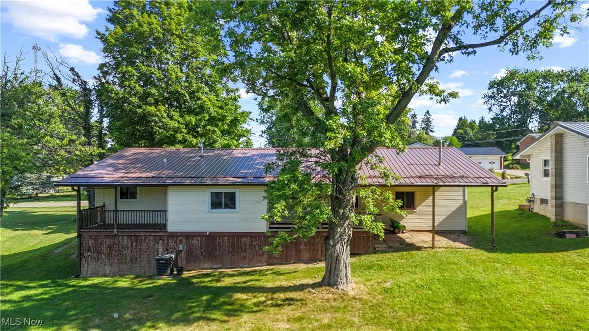 Rear view of house with a metal roof and a lawn