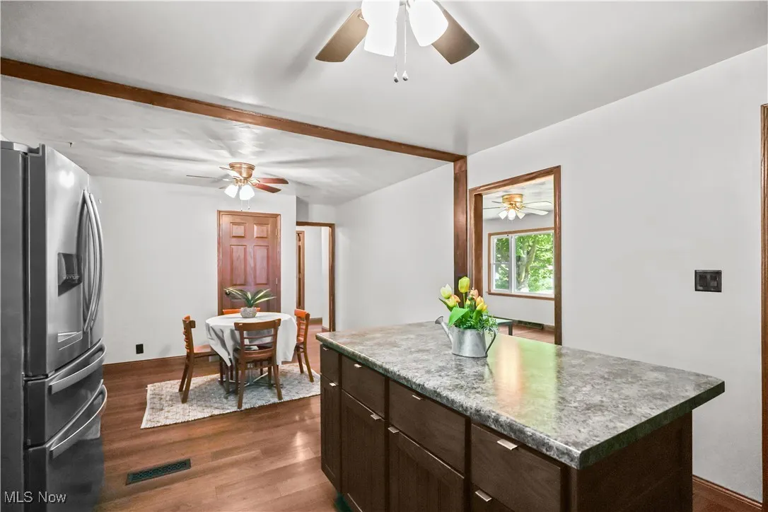 Kitchen featuring stainless steel fridge, ceiling fan, dark wood-style floors, and beamed ceiling