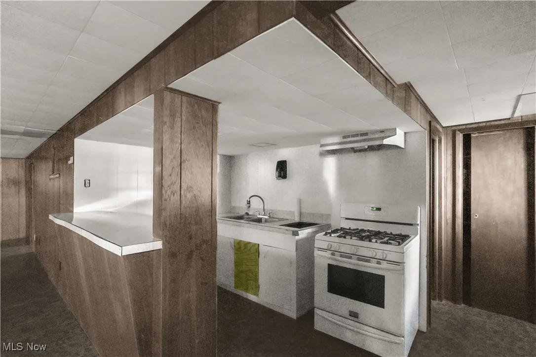 Kitchen with gas range gas stove, ventilation hood, a paneled ceiling, and dark carpet
