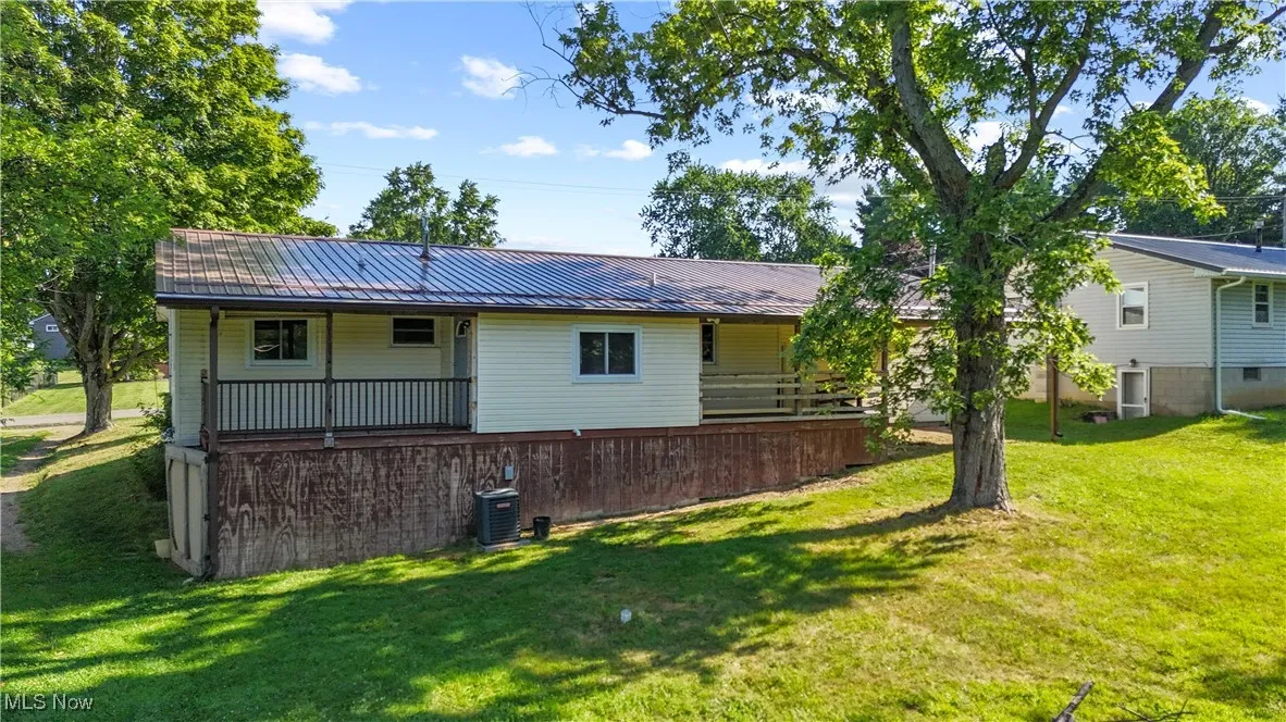 Back of house featuring a metal roof, a yard, and covered porch