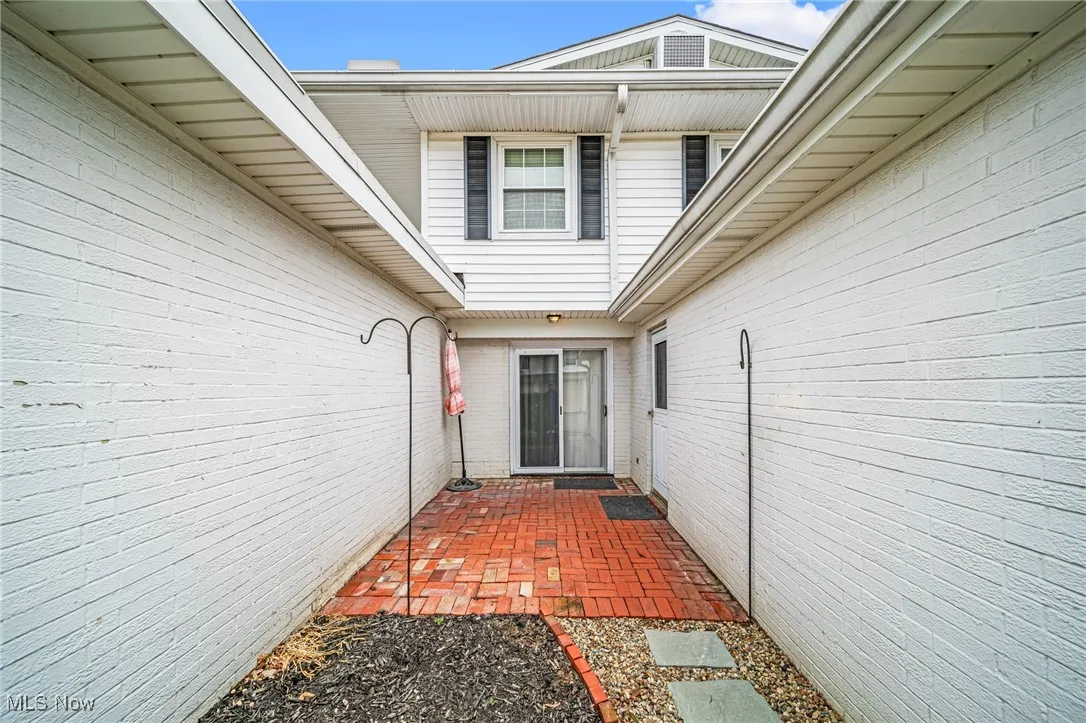 Doorway to property featuring a patio area and brick siding