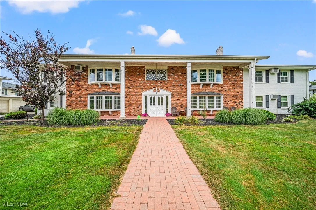 View of front of property featuring a chimney, a front lawn, and brick siding