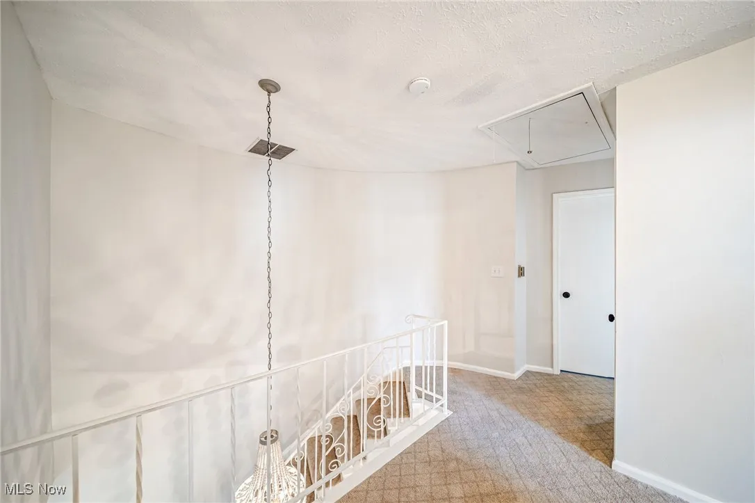 Hall featuring attic access, carpet, an upstairs landing, and a textured ceiling