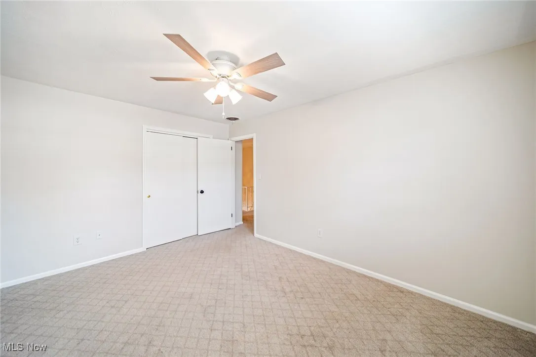 Unfurnished bedroom with light carpet, a closet, and a ceiling fan