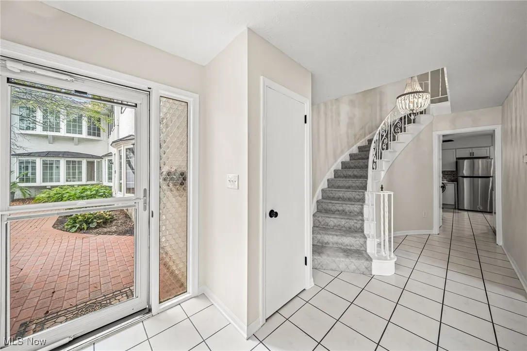 Entryway with a chandelier, stairway, and light tile patterned floors