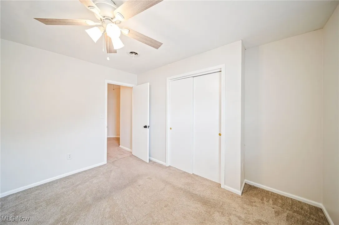 Unfurnished bedroom with light carpet, a closet, and a ceiling fan