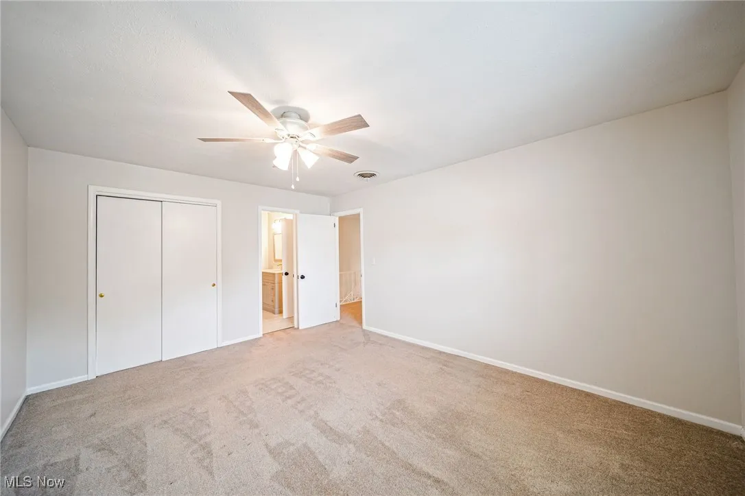 Unfurnished bedroom with carpet floors, a closet, a ceiling fan, and ensuite bathroom