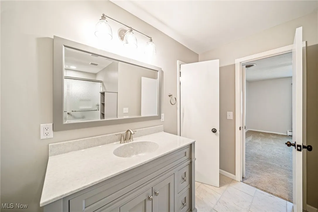Full bath with vanity, marble finish flooring, and a shower