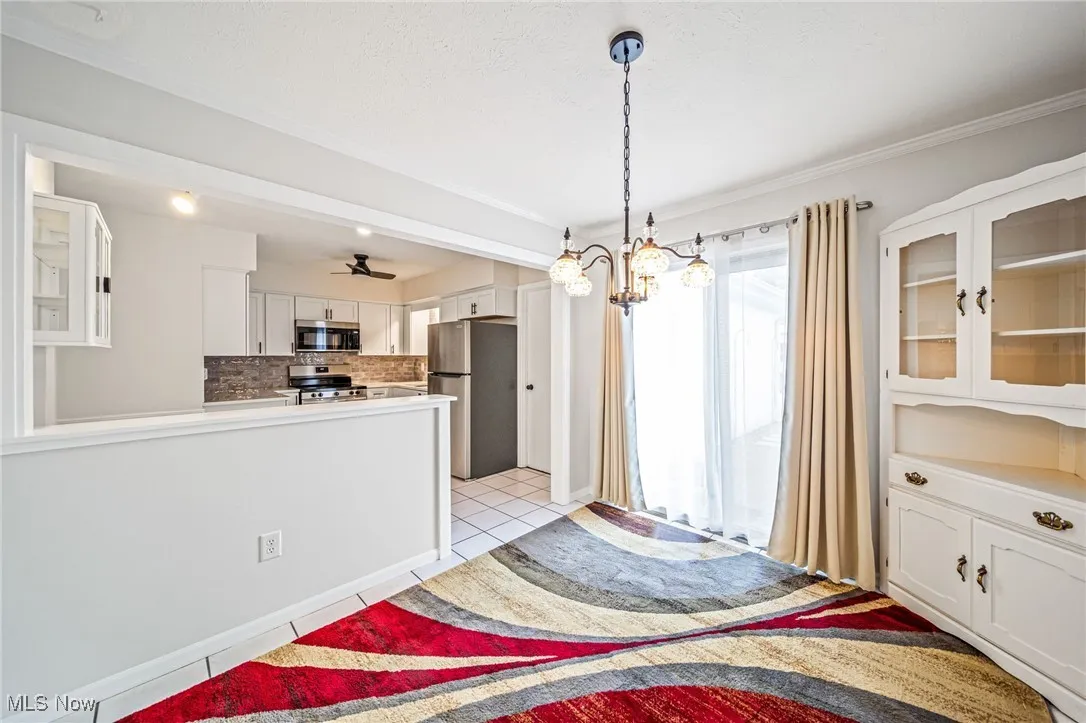 Kitchen featuring appliances with stainless steel finishes, white cabinetry, glass insert cabinets, tasteful backsplash, and crown molding