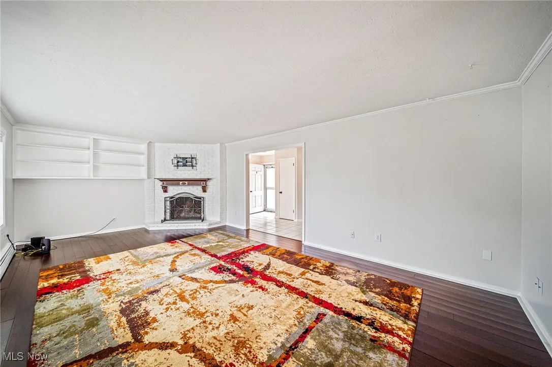 Unfurnished living room featuring hardwood / wood-style floors, crown molding, and a fireplace