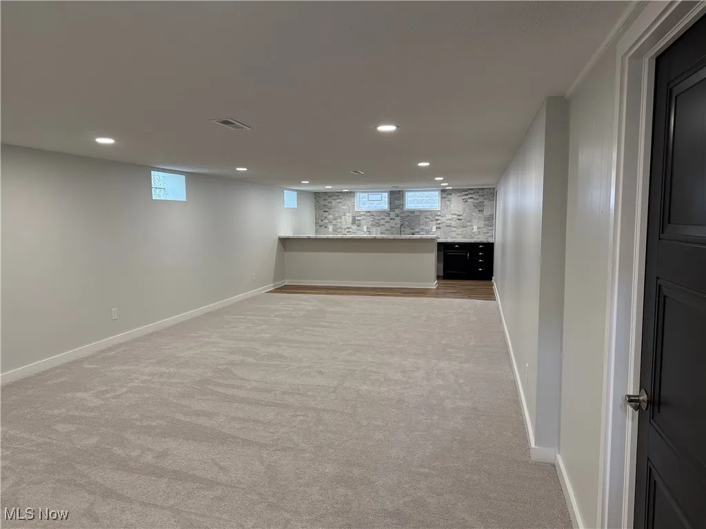 Below grade area featuring recessed lighting and light carpet
