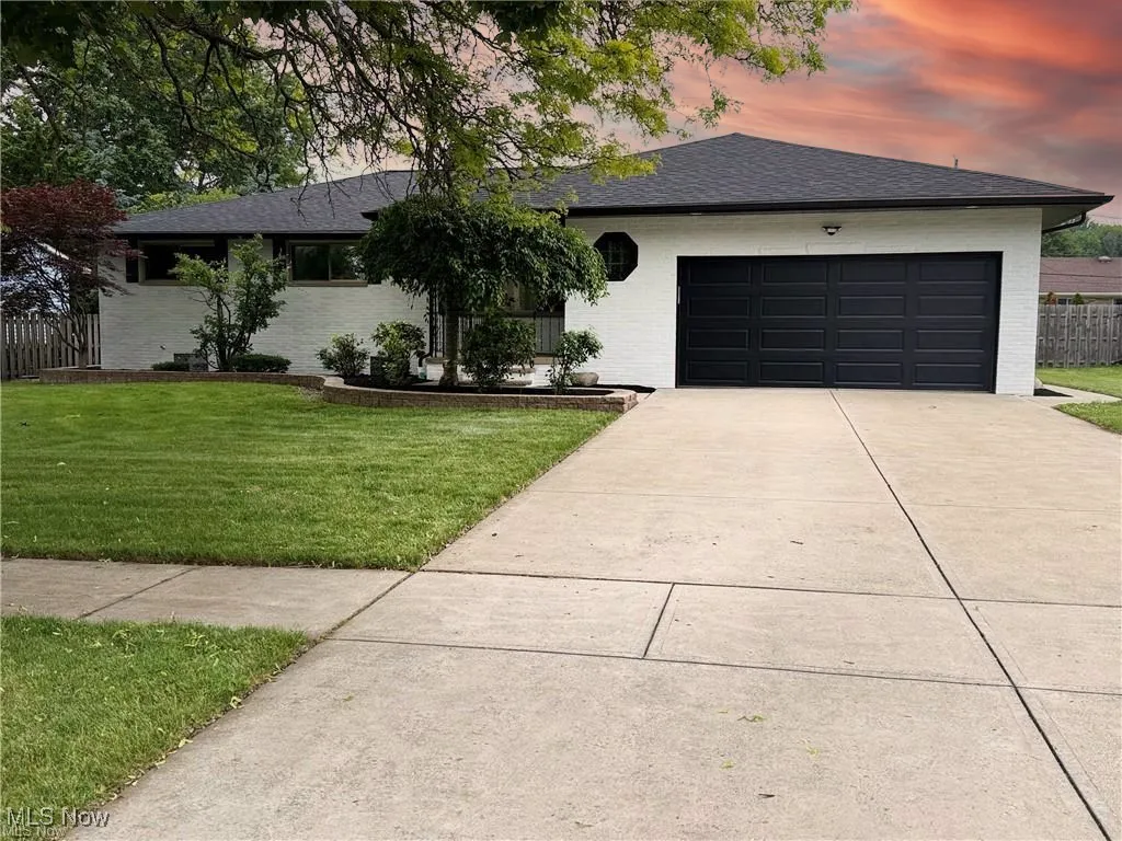 Ranch-style home featuring driveway, an attached garage, brick siding, and a shingled roof