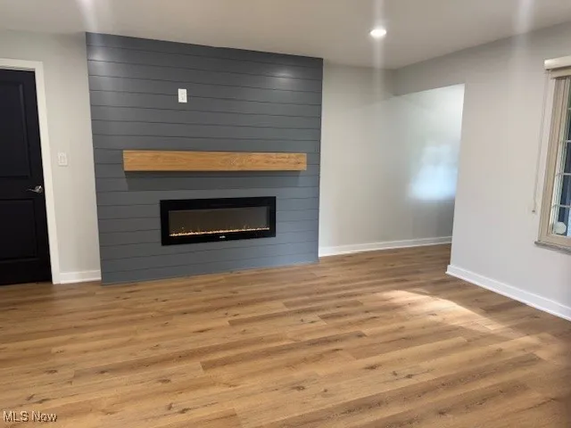 Unfurnished living room with wood finished floors and a large fireplace