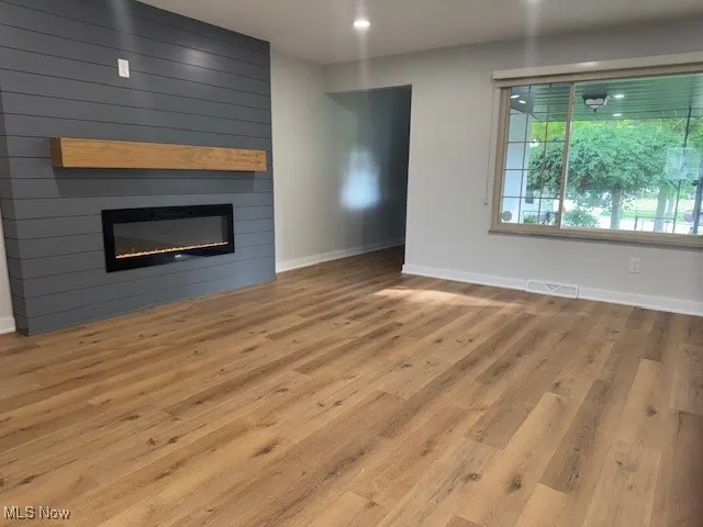 Unfurnished living room featuring a large fireplace, wood finished floors, and recessed lighting