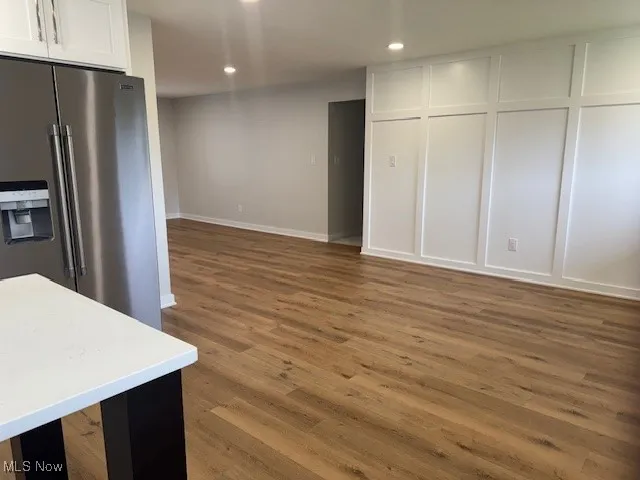 Kitchen with high end refrigerator, wood finished floors, white cabinetry, recessed lighting, and light countertops