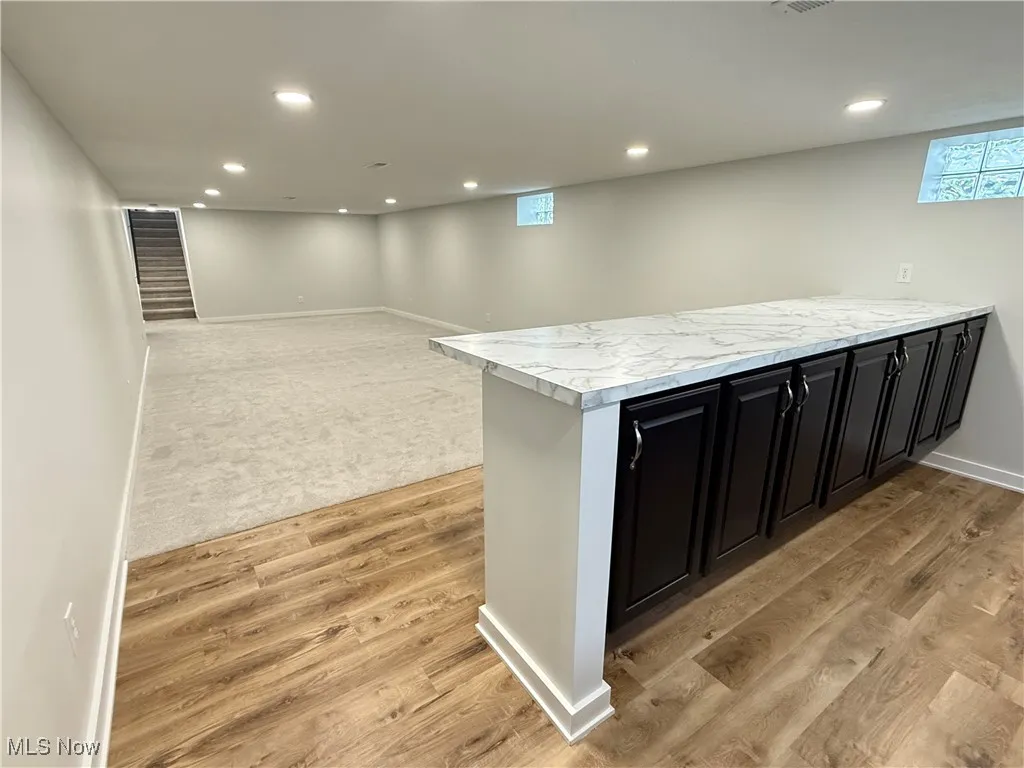 Kitchen featuring dark cabinetry, light wood-style floors, recessed lighting, a peninsula, and light carpet