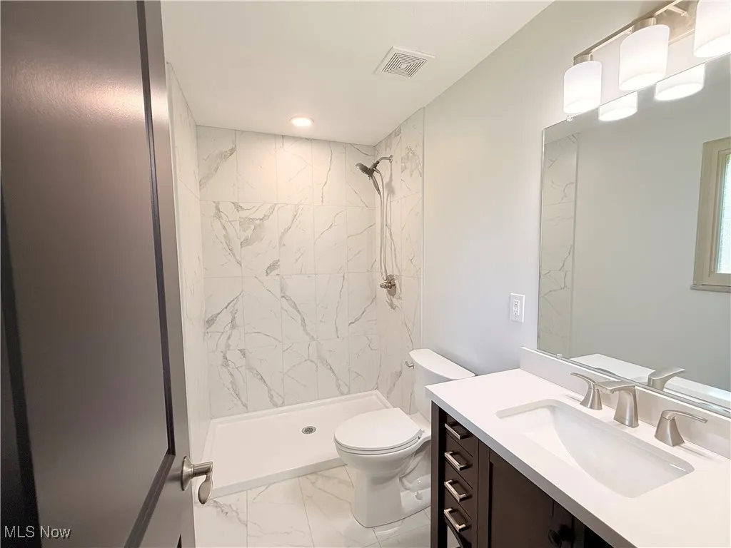 Bathroom with marble finish floors, a shower stall, vanity, and recessed lighting