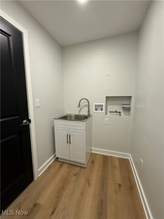 Laundry area featuring light wood-type flooring, hookup for a washing machine, and cabinet space