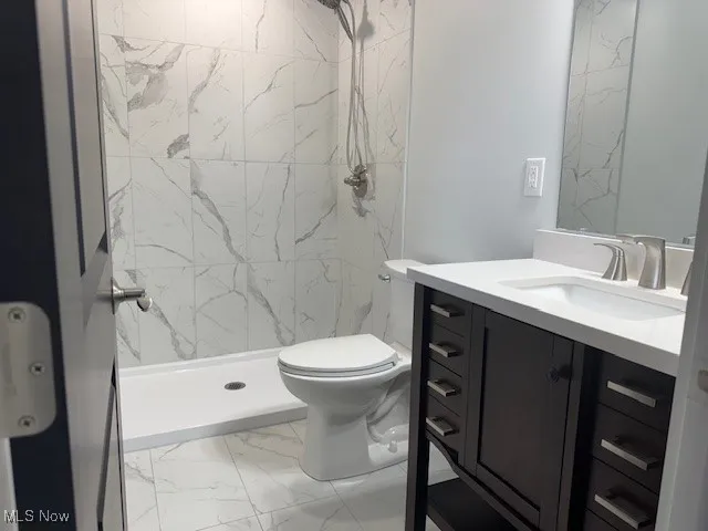 Bathroom with marble look tiles, vanity, and a shower stall