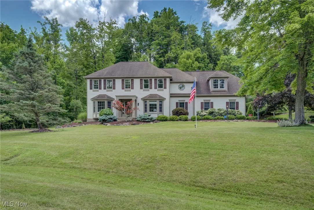 Colonial inspired home featuring a front yard and view of scattered trees