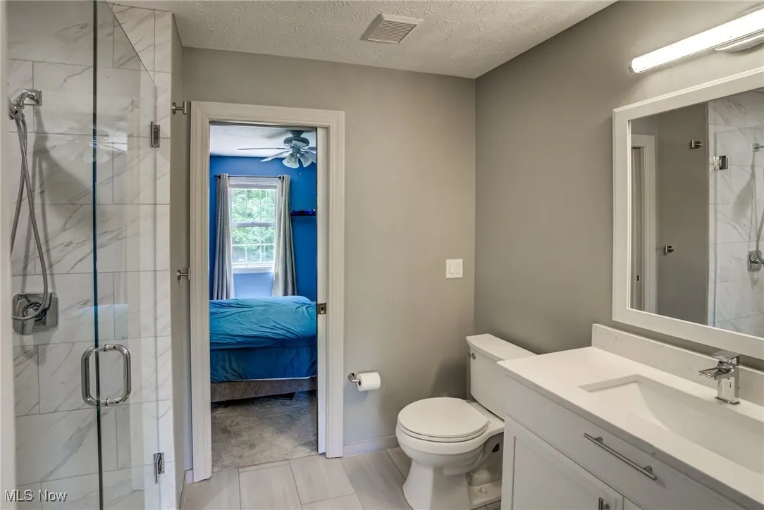 Full bathroom featuring vanity, a marble finish shower, ensuite bath, and a textured ceiling