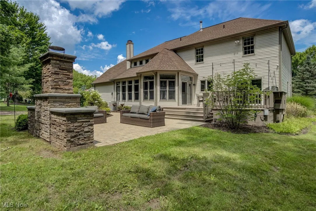 Rear view of house featuring a patio, a yard, a wooden deck, and a chimney