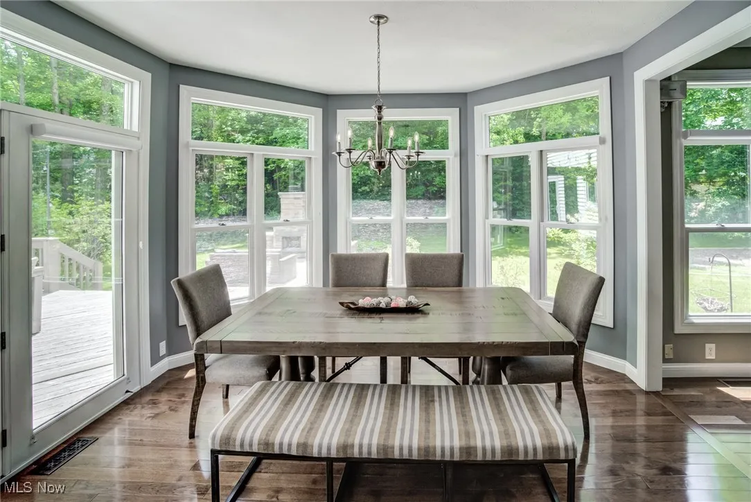 Sunroom / solarium with wood finished floors, a chandelier, and a wooden deck