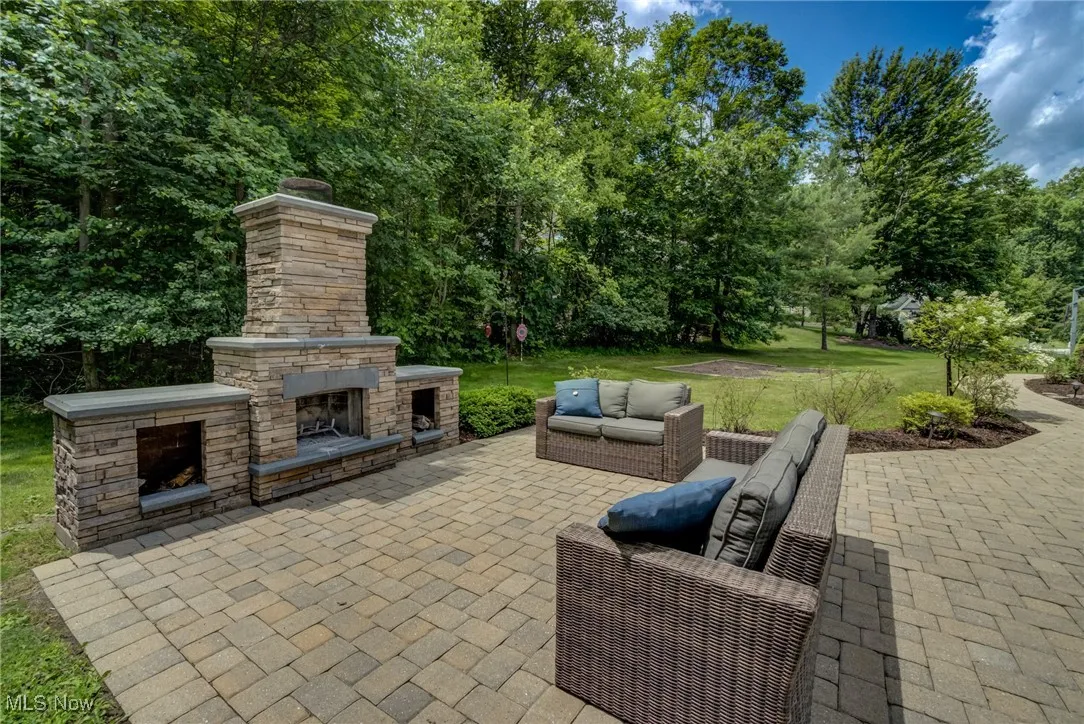 View of patio with an outdoor living space with a fireplace and view of wooded area
