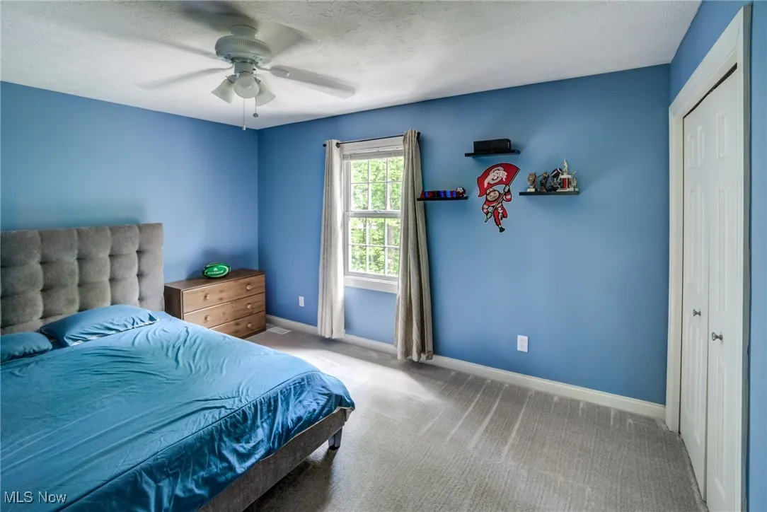 Carpeted bedroom with a ceiling fan and a textured ceiling